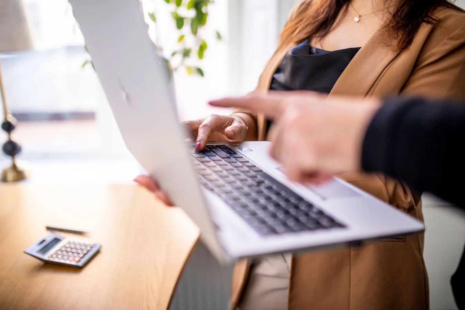 En kvinna pekar på en bärbar dator.