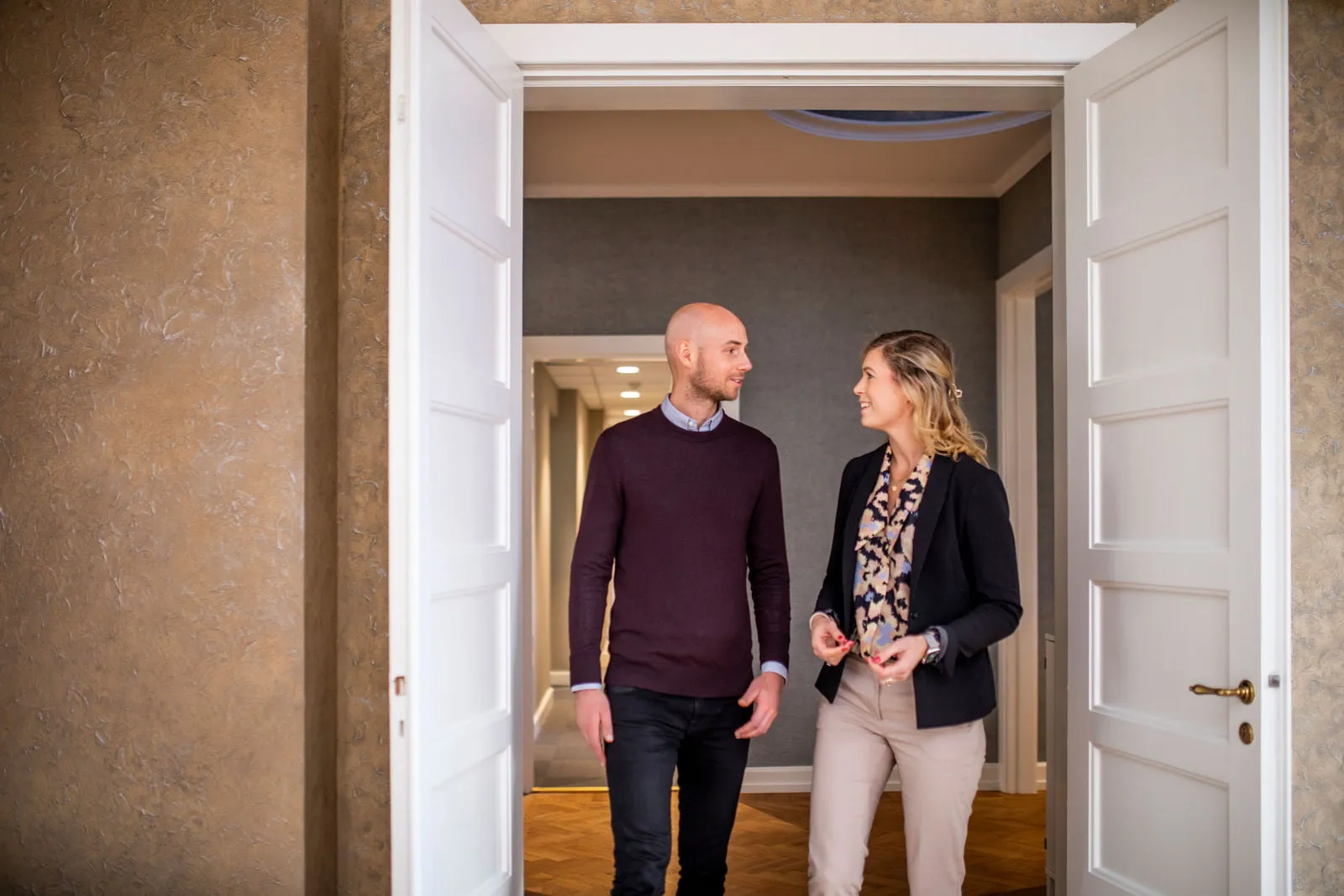 En man och en kvinna står och pratar med varandra i en stor dörröppning för dubbeldörr.