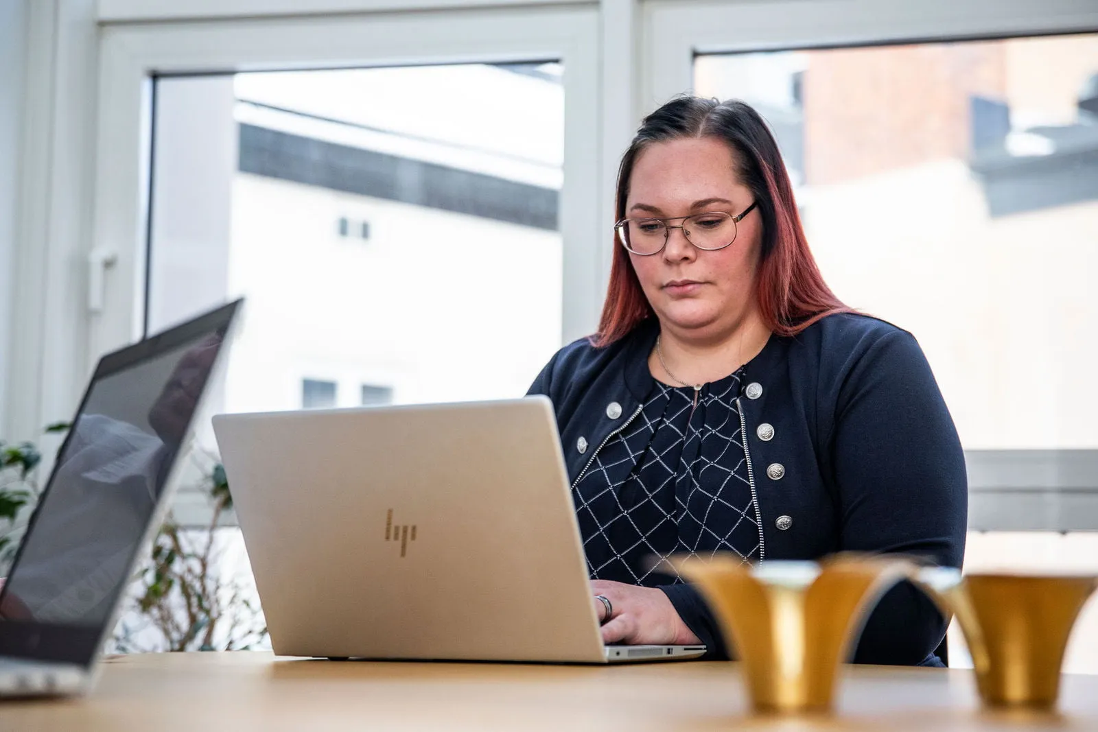 En kvinna sitter fokuserad vid ett skrivbord och skriver på sin bärbara dator.